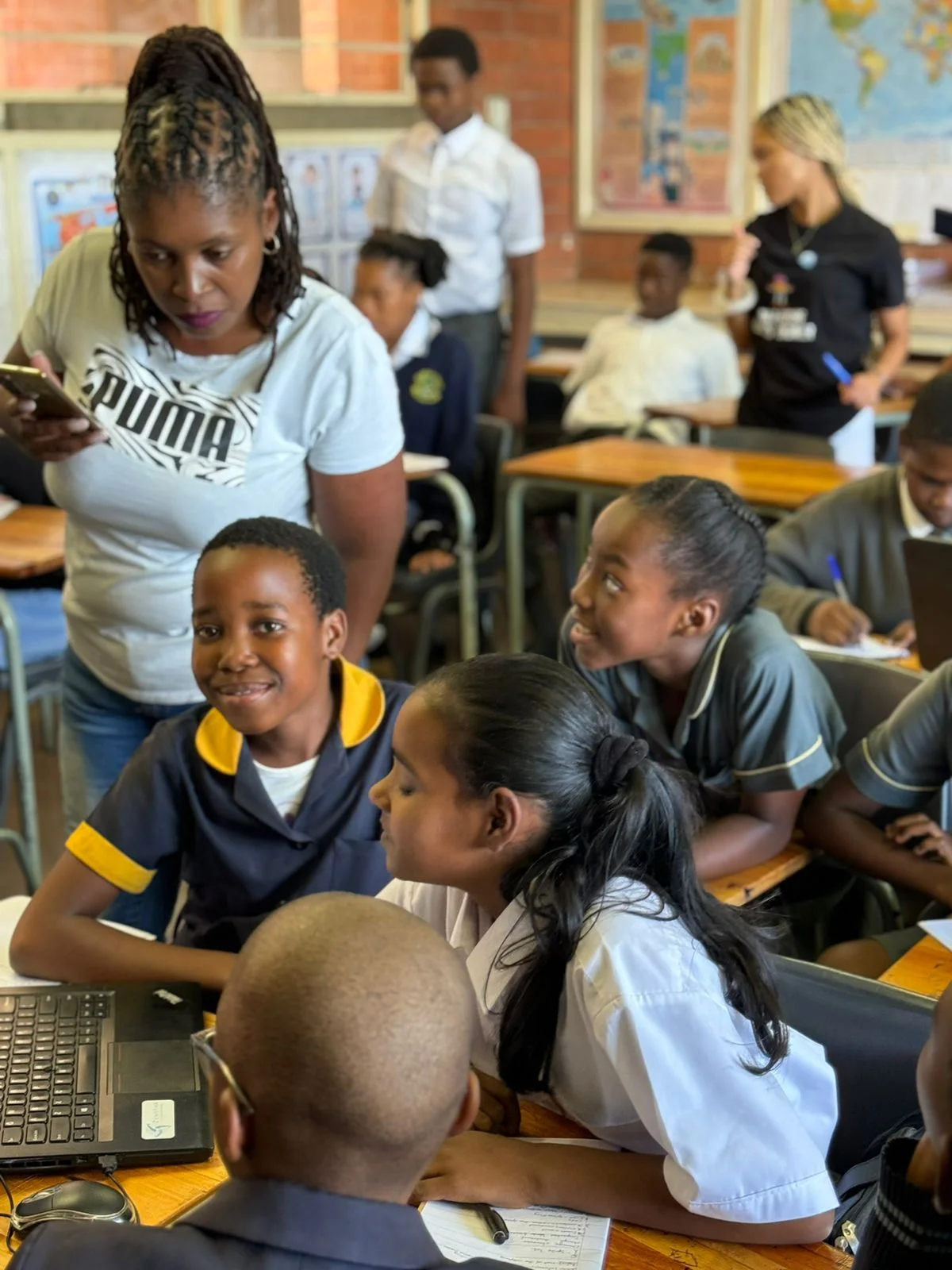 Learners and a facilitator gathered around a classroom laptop